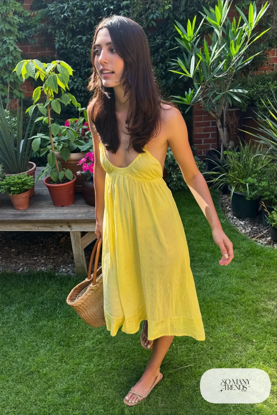 Woman in a lemon yellow eyelet cotton sundress with flat woven sandals and a straw tote, garden party outfit 6