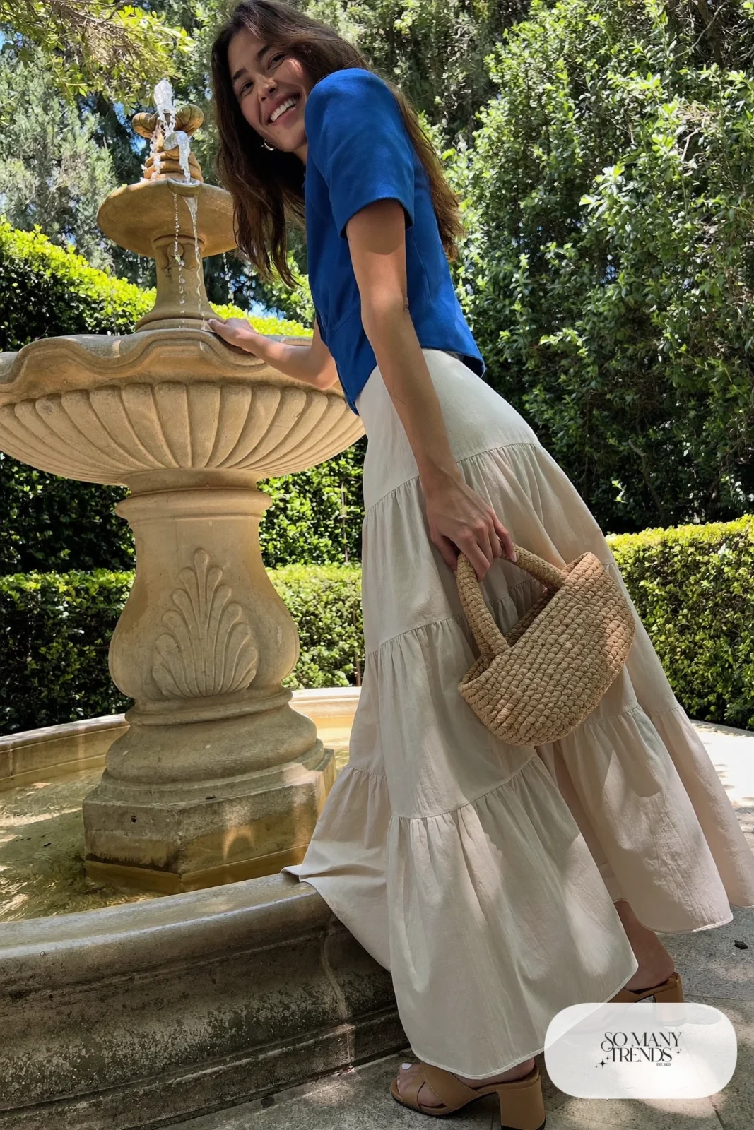 Woman in a cobalt blue cotton top and cream tiered midi skirt with tan block-heel sandals, garden party outfit 18