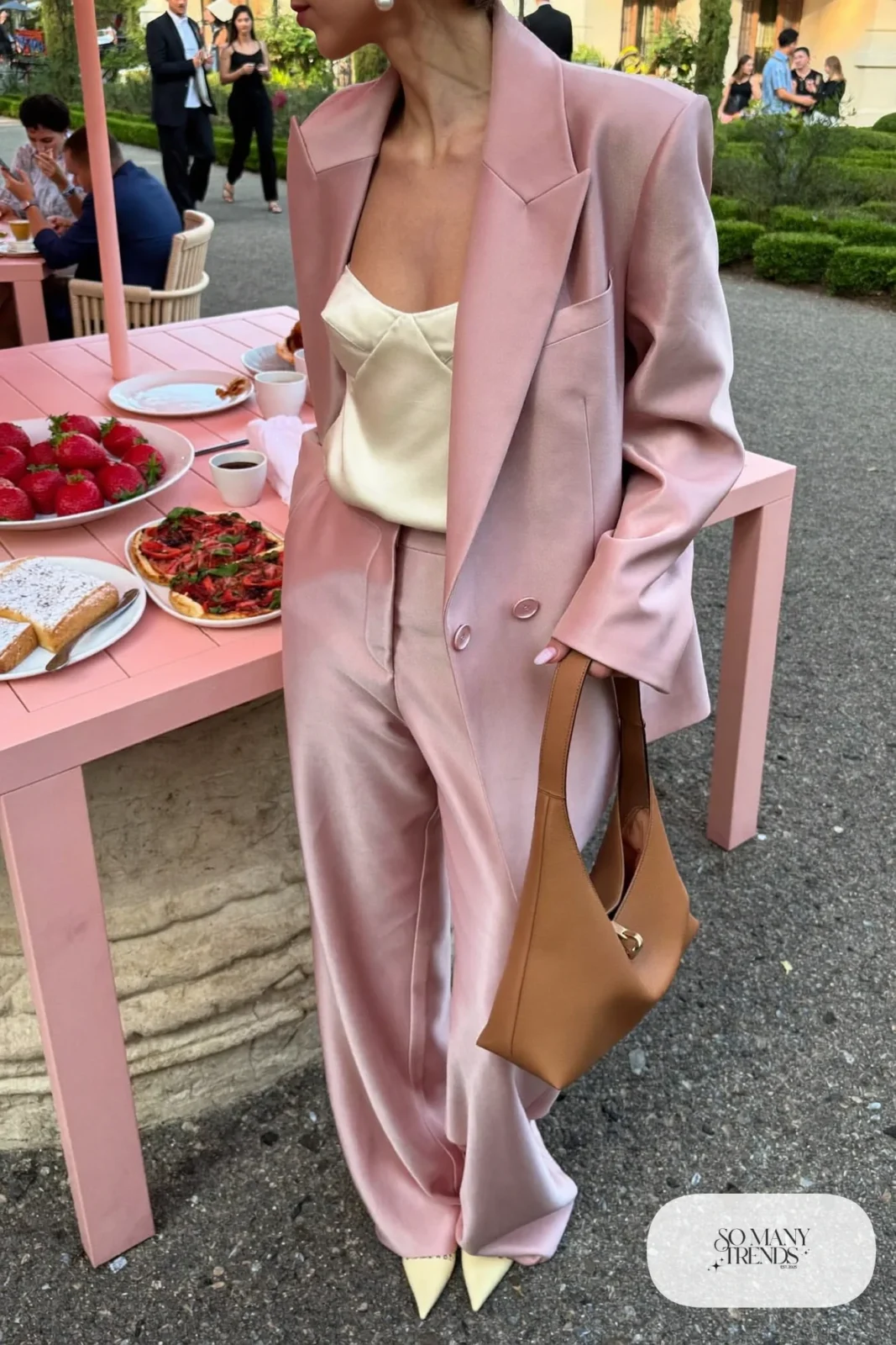 Woman in a blush pink oversized blazer, matching wide-leg pants, cream cami and kitten heels at a brunch table, look 3