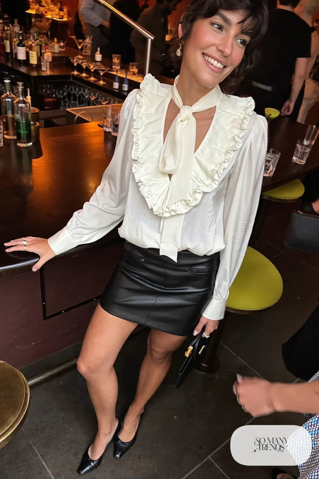 Look 2: ivory ruffled bow-neck blouse, black faux leather skirt, black block-heel pumps, small clutch