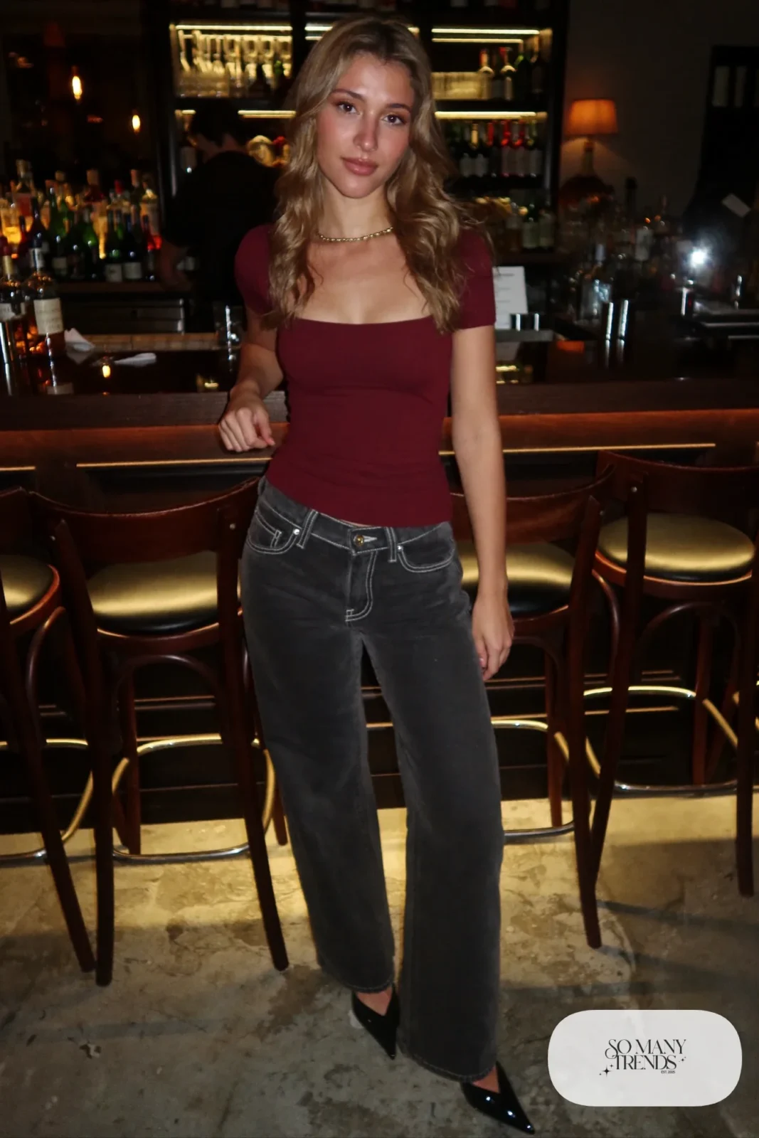 Look 18: burgundy fitted knit top with a square neckline, dark wide-leg jeans, black pointed heels, thin gold necklace