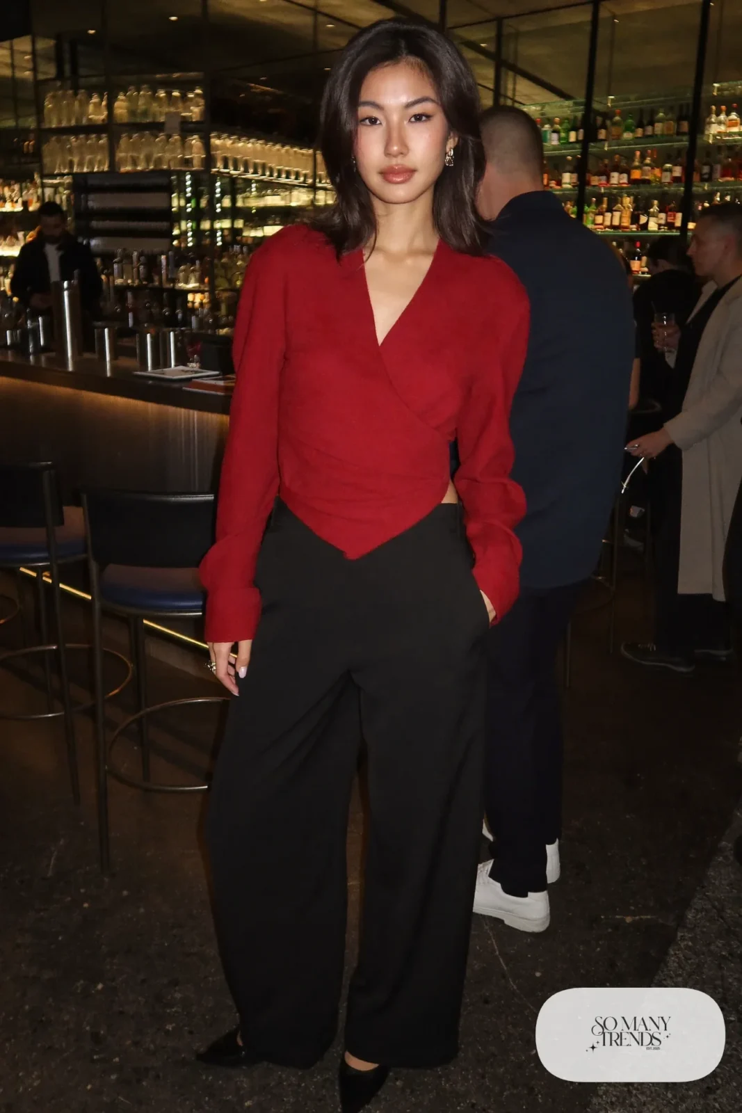 Look 23: deep red wrap top with a V neckline, black wide-leg pants, black pointed heels, small earrings