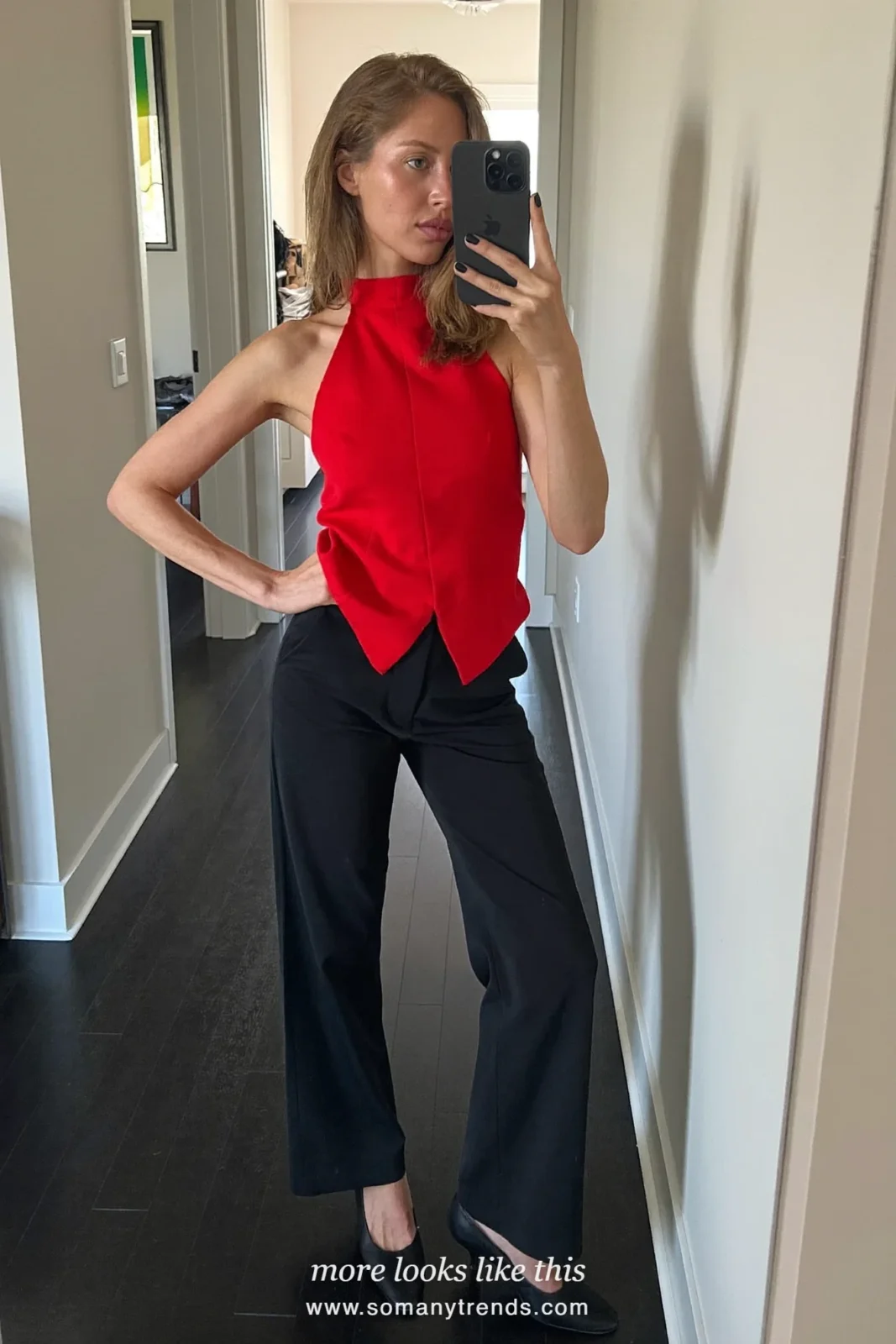 Woman in a cherry red halter top, black wide-leg pants and black heels taking a mirror selfie in a hallway, outfit 4