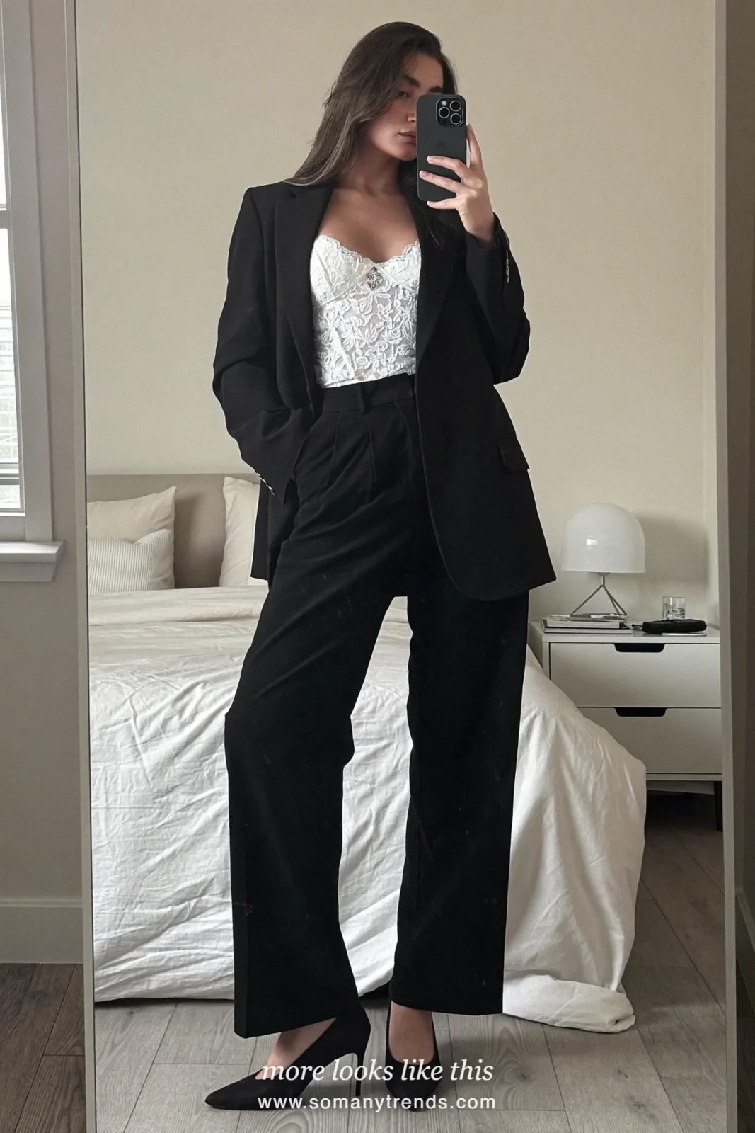 Woman in a white lace cami, black long relaxed blazer, black wide-leg pants and black pumps taking a mirror selfie, outfit 12