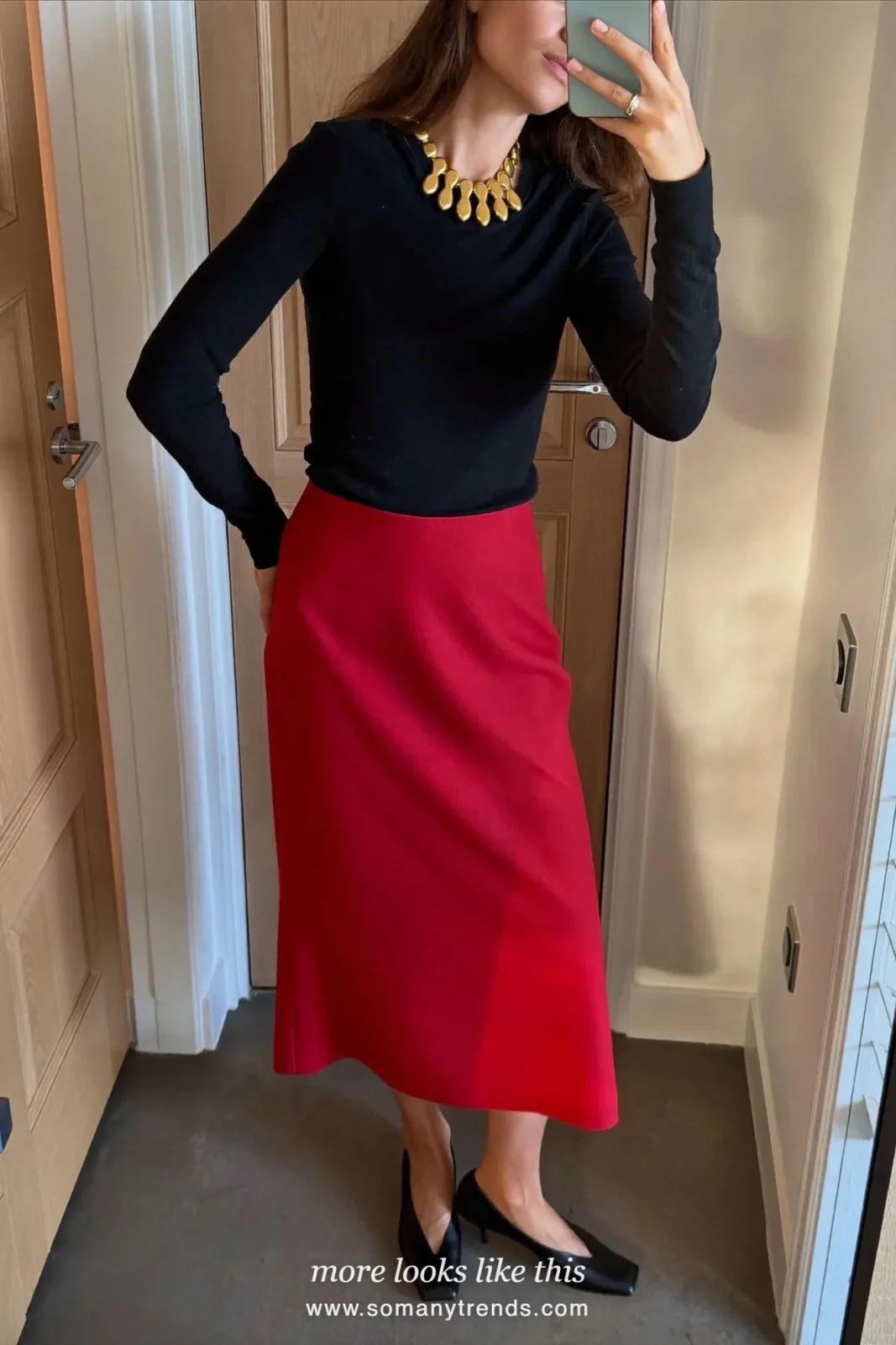 Woman in a black long-sleeve top, red crepe midi skirt, statement necklace and black pumps taking a mirror selfie, outfit 32