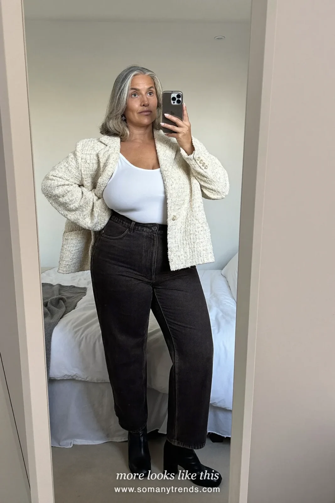 Woman in a cream tweed boxy jacket, white camisole, dark straight jeans and ankle block-heel boots at a Christmas market, outfit 8