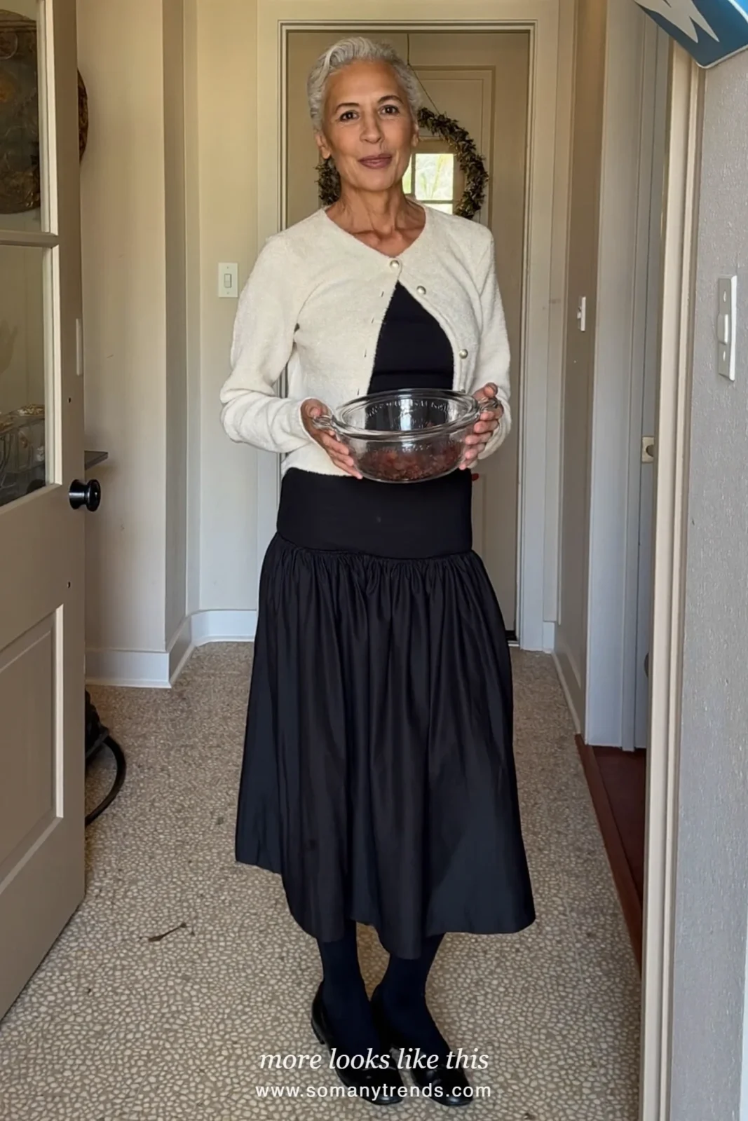 Woman in a cream pearl-button cardigan, black top, black midi skirt and ballet flats at a family Christmas afternoon, outfit 13
