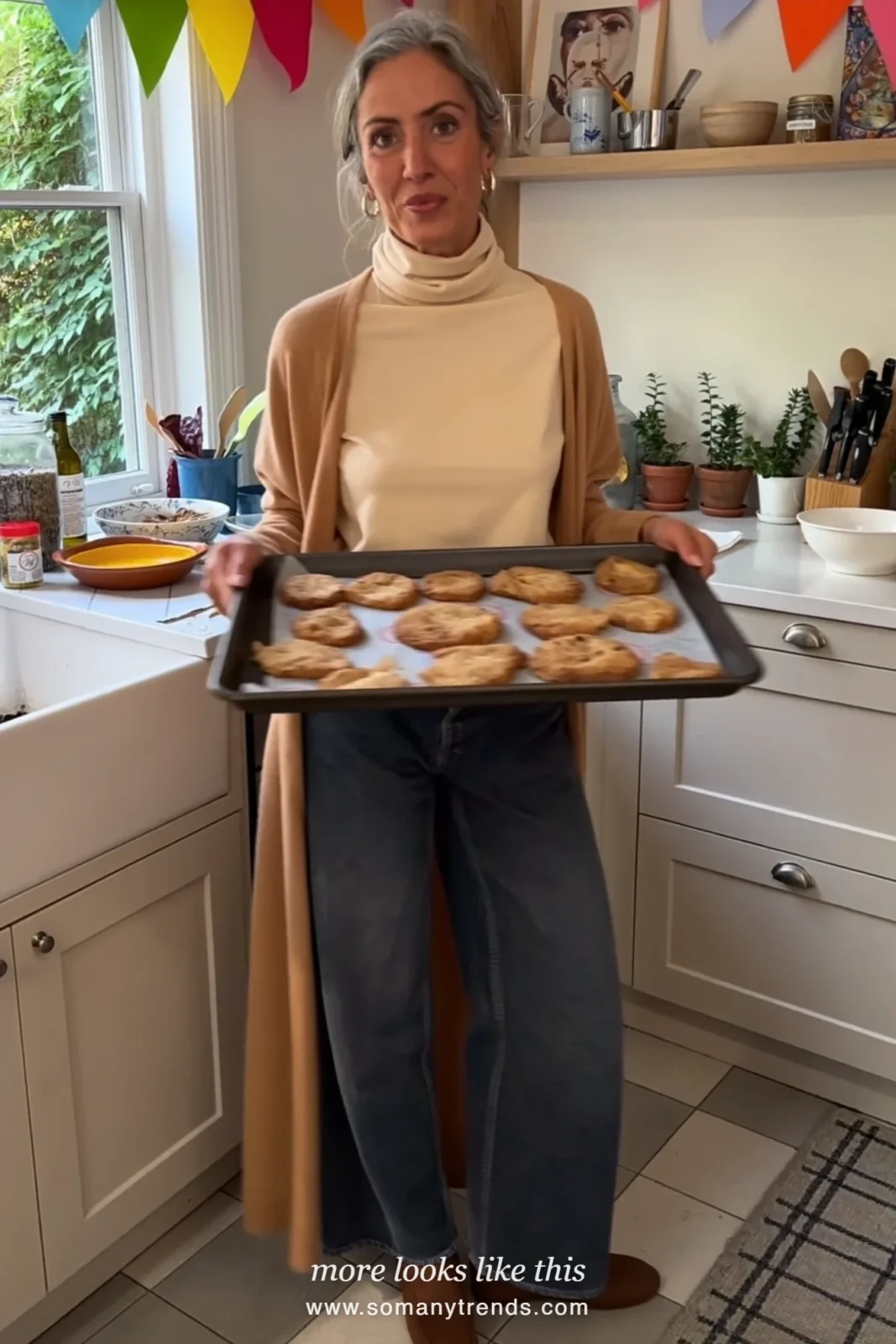 Woman in a cream turtleneck, long camel cardigan, straight dark jeans and low boots while hosting Christmas, outfit 27
