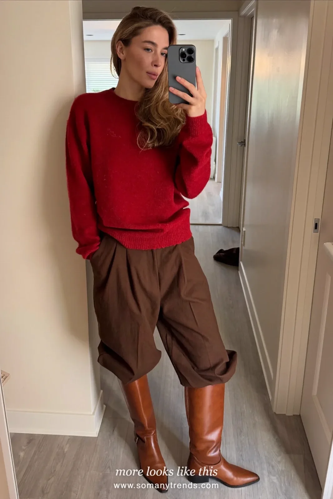 Woman taking a mirror selfie in a deep red sweater, wide chocolate brown pants and brown riding boots, outfit 4