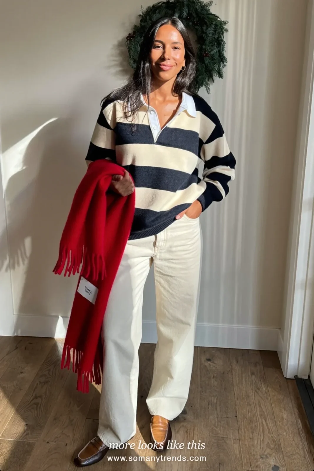 Woman in a navy and cream striped rugby sweater, cream pants and loafers holding a red scarf, outfit 10