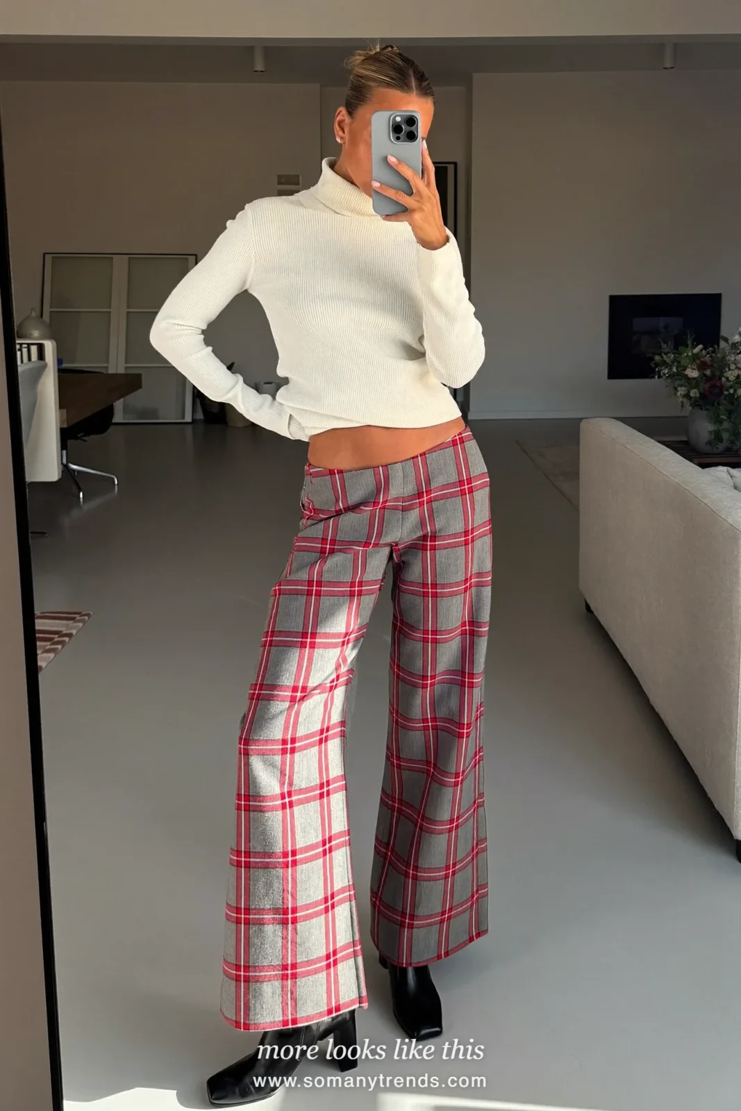 Woman in gray and red plaid flannel pants, ivory turtleneck and black block heel boots in a living room, outfit 12