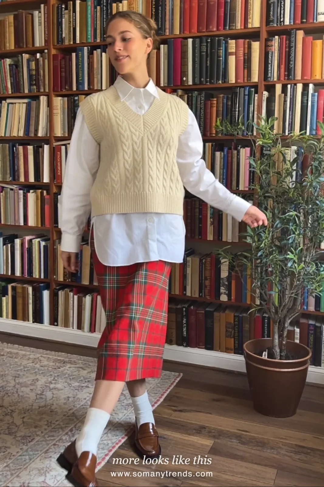 Woman in a white oxford shirt, cream cable knit vest, tartan skirt and loafers in a study, outfit 14