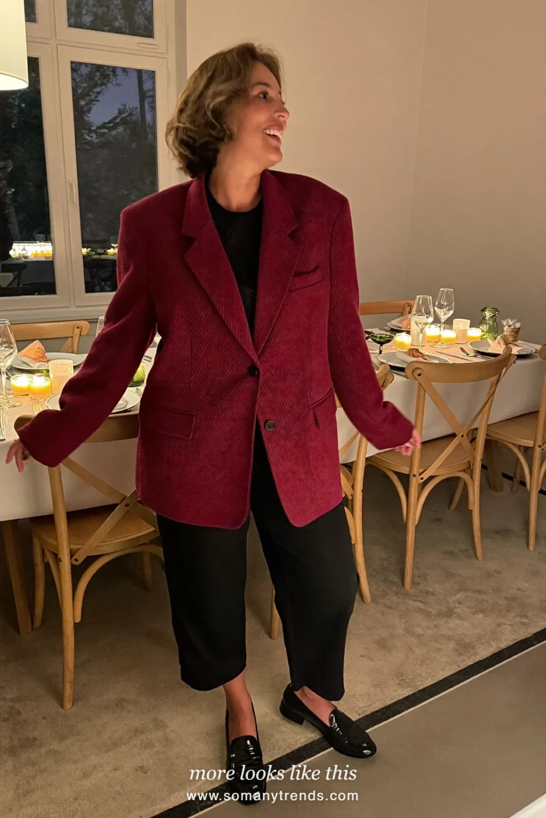 Woman in a deep red blazer, black knit top, black straight pants and black loafers at a candlelit dinner, outfit 19