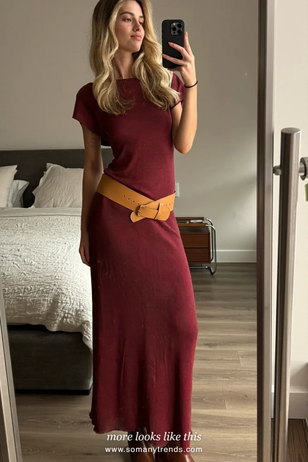 Woman in a burgundy knit maxi dress, wide camel belt and brown boots in a living room, outfit 20