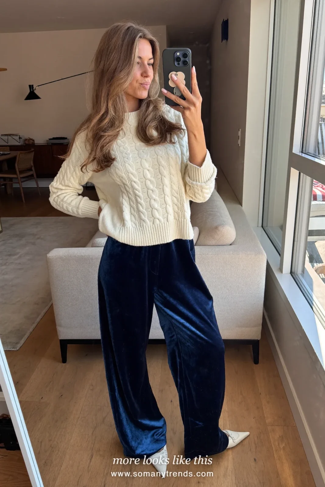 Woman in wide navy velvet pants, ivory cable knit sweater and cream flats at a dinner, outfit 24