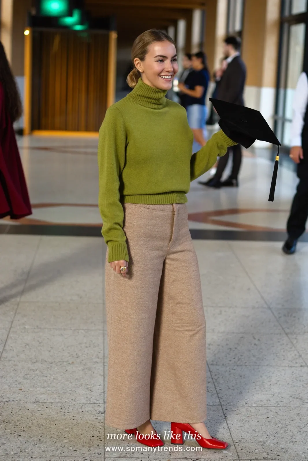 Woman wearing a pine green fine-knit turtleneck, wide-leg oatmeal wool pants and red block-heel pumps, winter graduation outfit 1