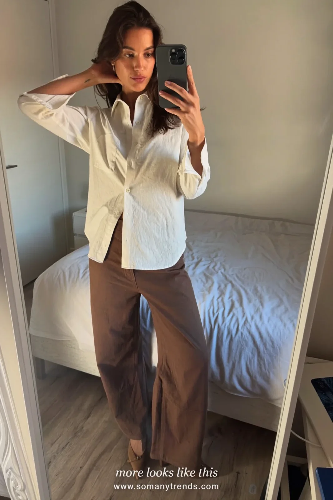 Woman taking a bedroom mirror selfie in an ivory shirt, wide chocolate brown pants and brown pumps, spring church outfit 24