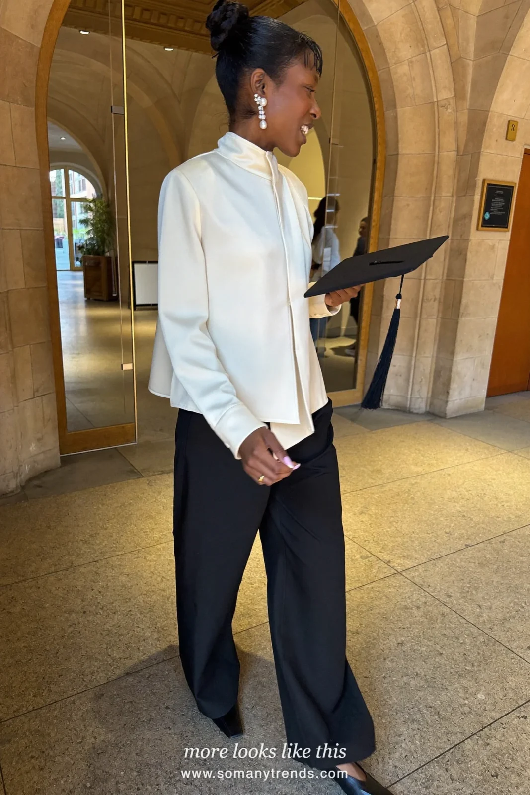 Woman wearing an ivory high-neck blouse, wide-leg black pants, pearl drop earrings and black pointed flats, winter graduation outfit 21