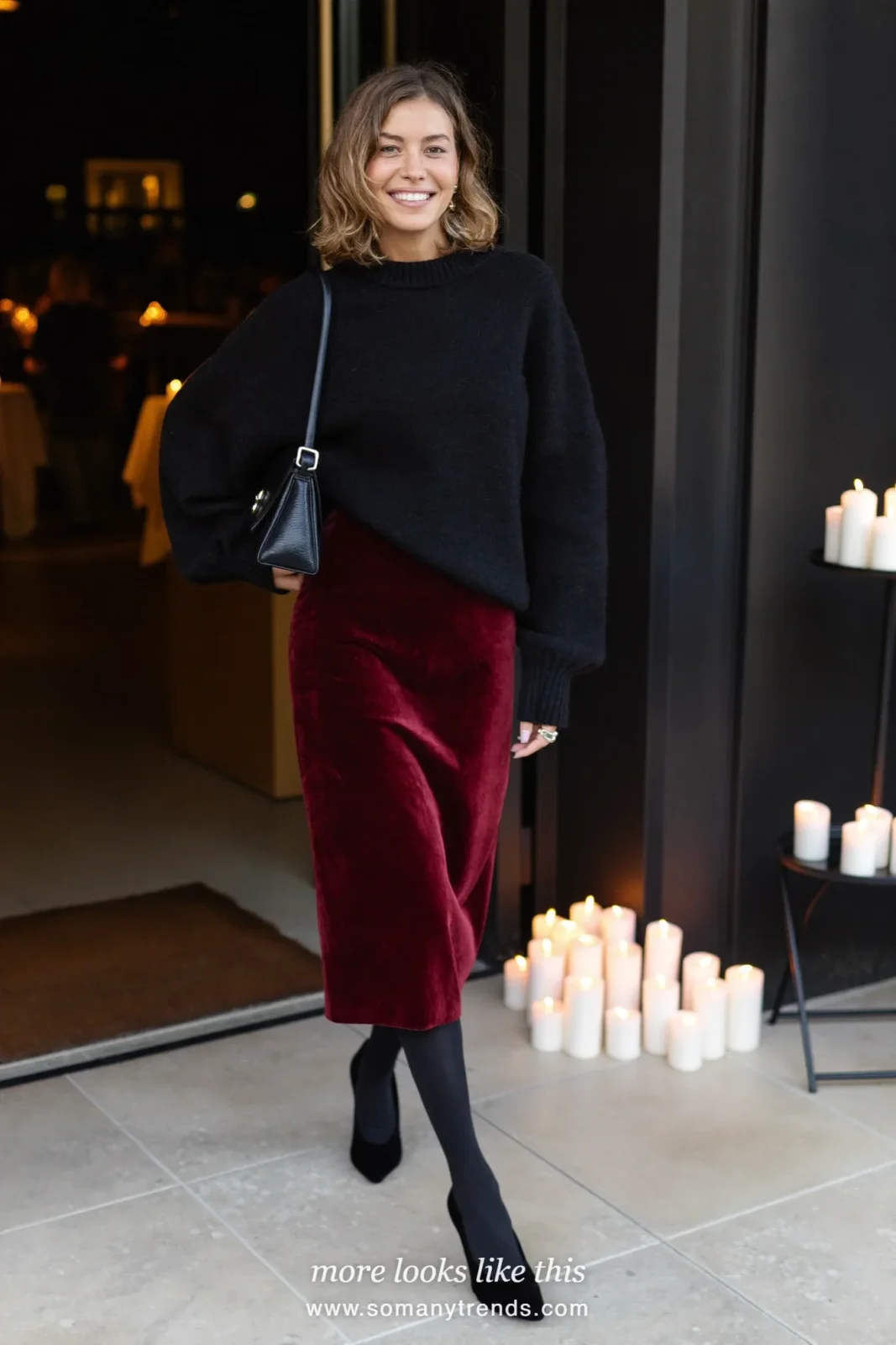 Woman in a burgundy velvet midi slip dress layered under a black fine knit sweater with black pumps, outfit 18