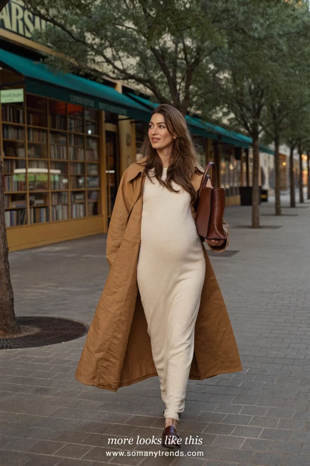 Woman with a baby bump in a long camel trench worn open over an ivory knit maxi dress and brown loafers, outfit 10