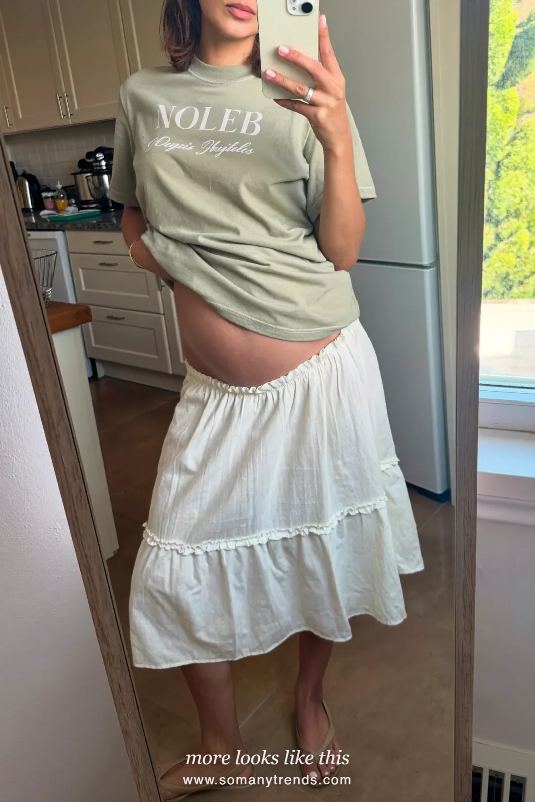 Woman with a baby bump in an ivory poplin midi maternity skirt, a loose sage tee and flat sandals, outfit 20