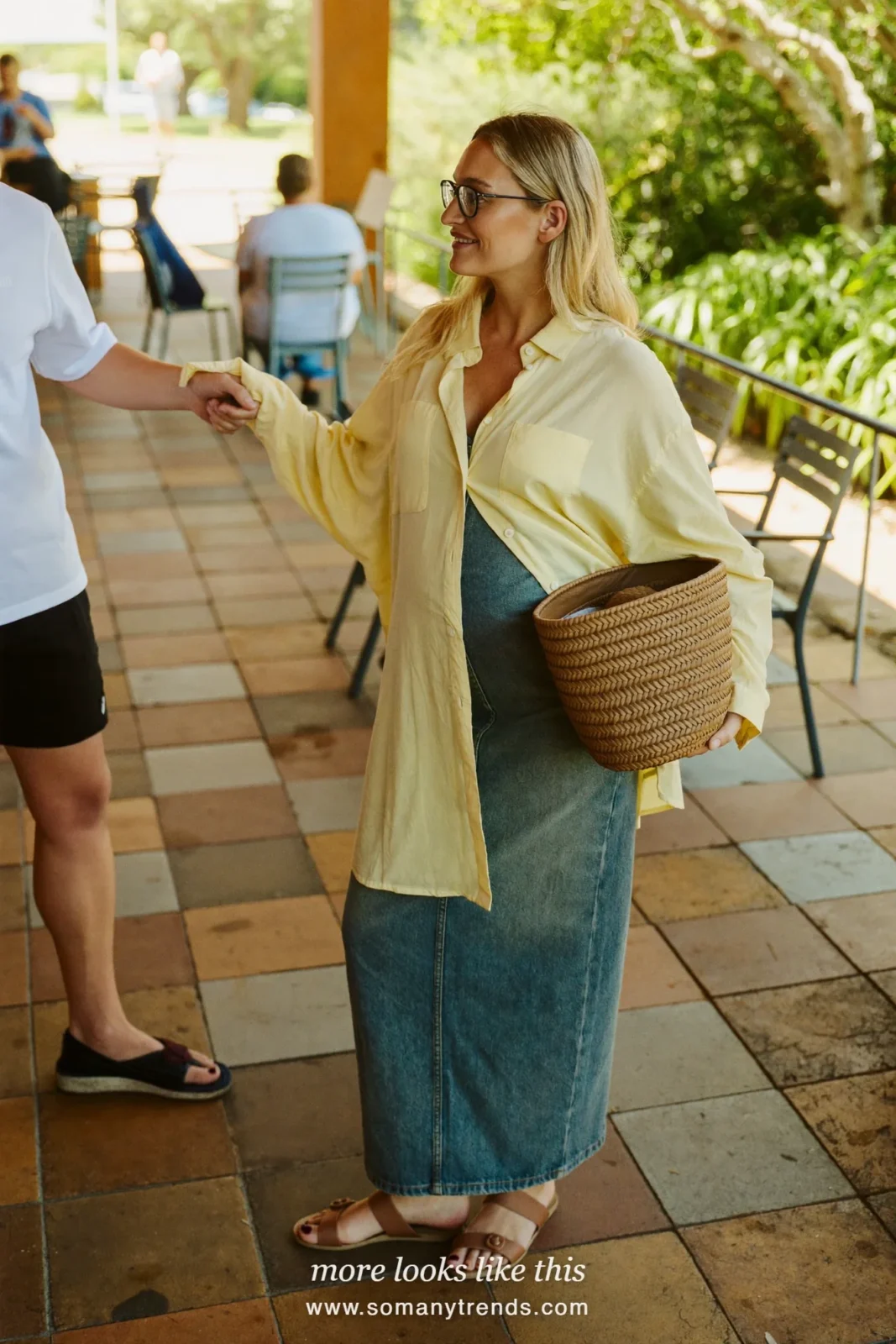 Woman with a baby bump in a butter yellow blouse, long faded denim maternity skirt and tan sandals, outfit 9
