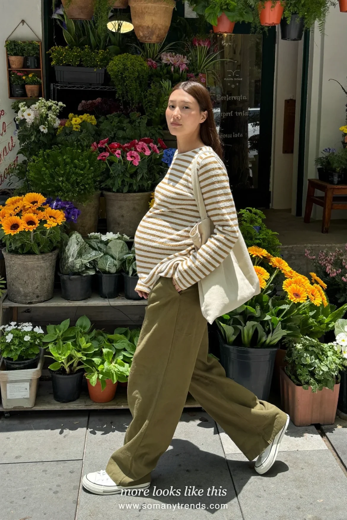 Woman with a baby bump in a long striped ivory and caramel tee, olive linen maternity pants and canvas sneakers, outfit 14