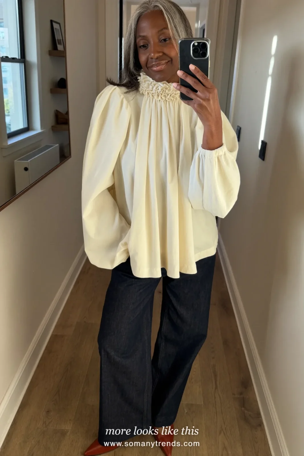 Woman in her forties wearing cream ruffled high-neck blouse, dark indigo straight jeans and terracotta pointed flats, outfit 4