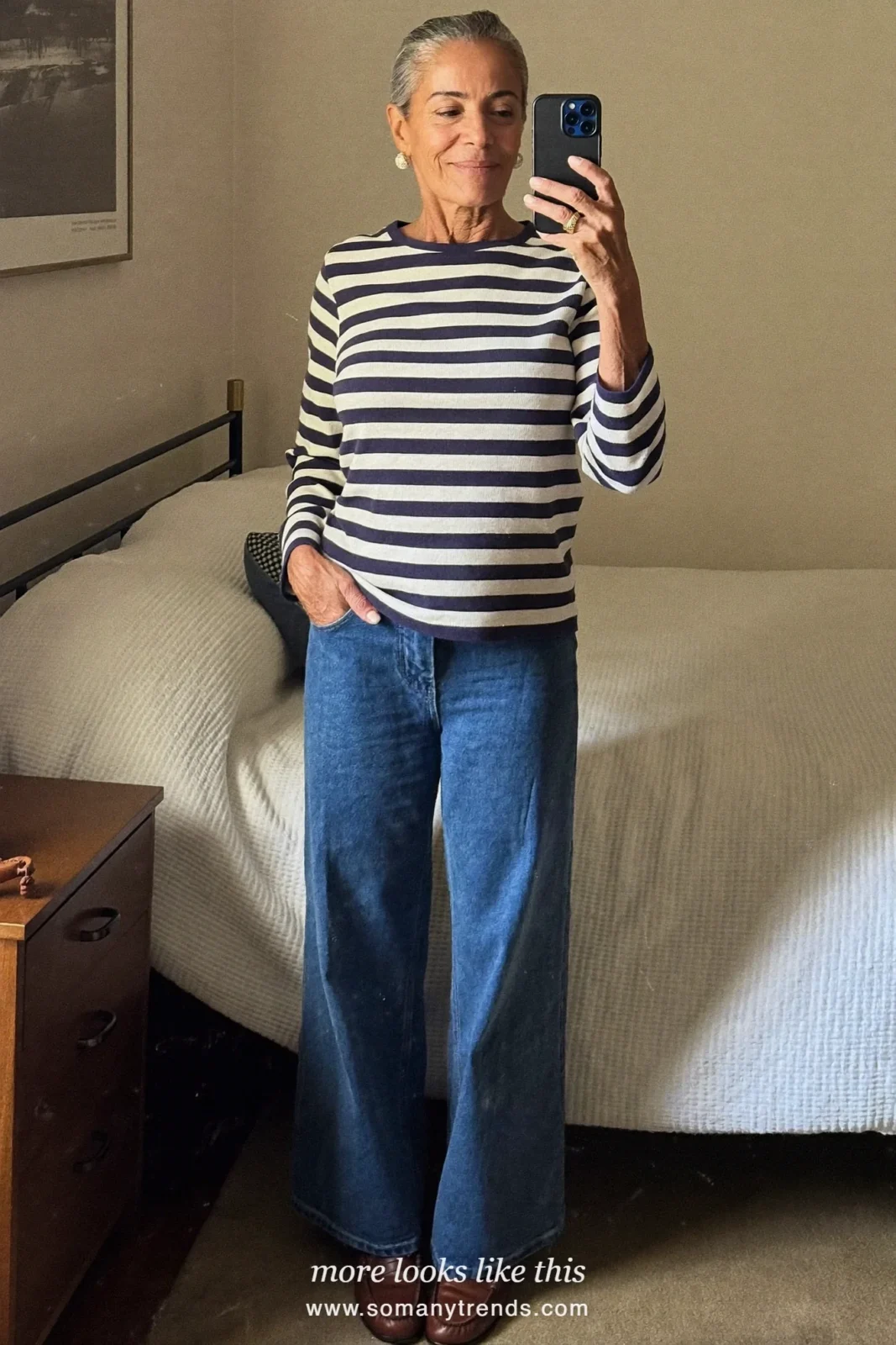 Woman in her forties wearing camel belted trench coat, navy and cream striped knit, straight blue jeans and brown loafers, outfit 8