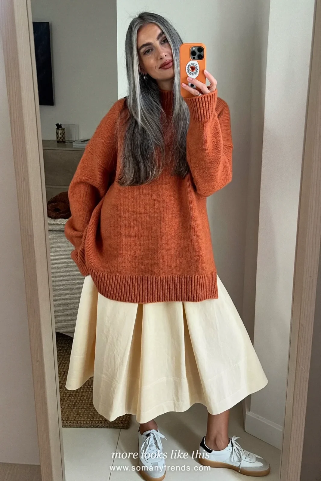 Woman in her forties wearing terracotta fine-knit sweater, cream pleated midi skirt and white leather sneakers, outfit 12