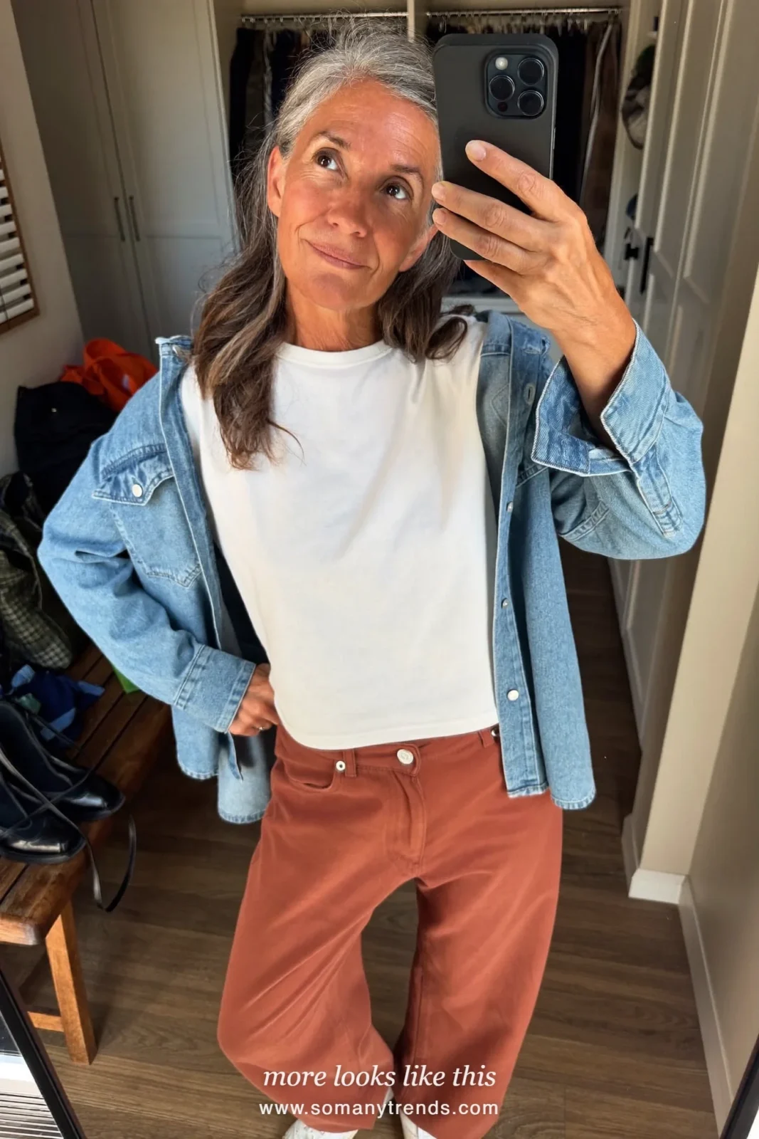 Woman in her forties wearing light-wash denim shirt open over white tee, terracotta straight twill pants and white sneakers, outfit 16