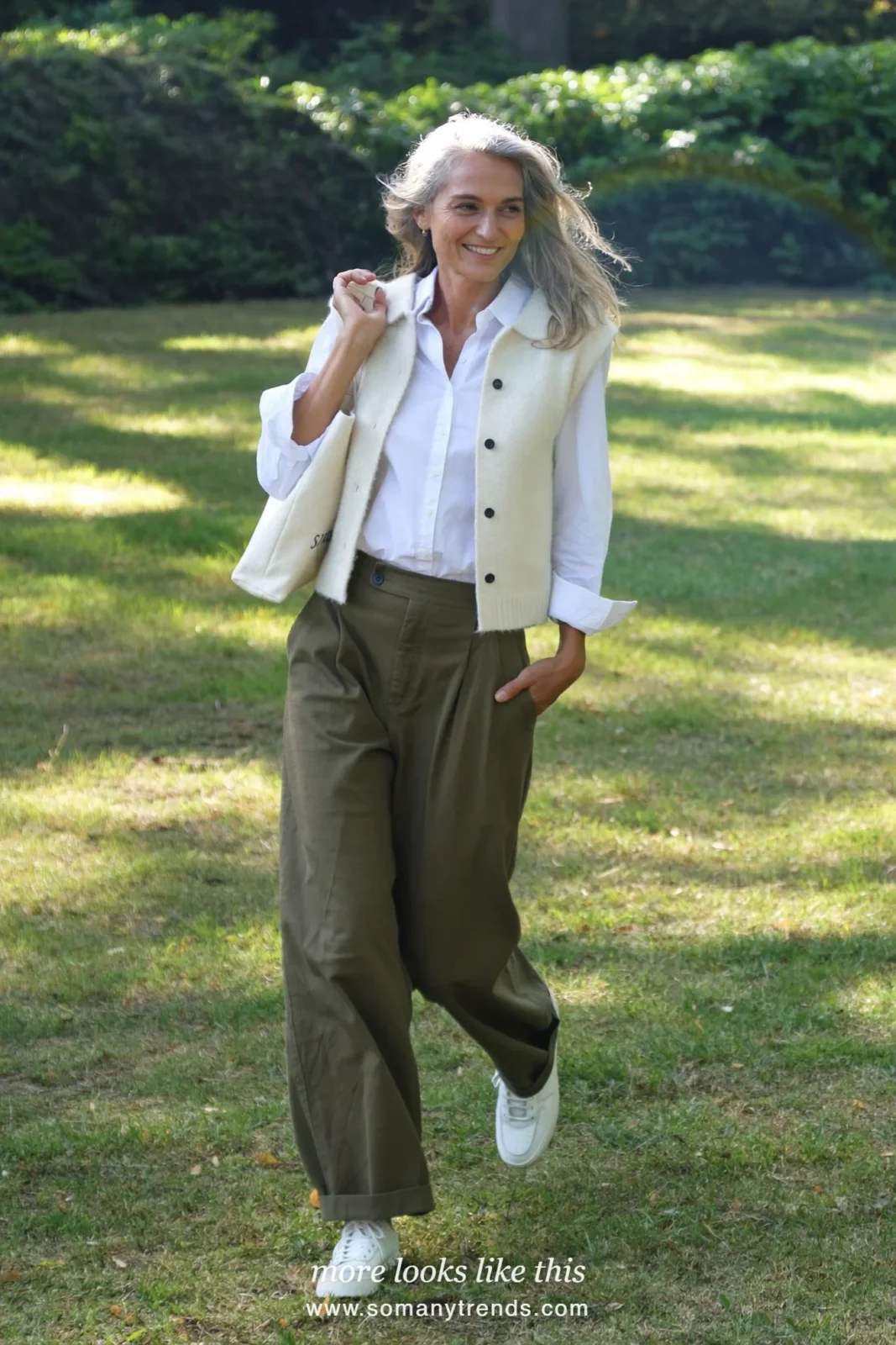Woman in her forties wearing cream sleeveless knit vest over white shirt, olive wide-leg pants and white leather sneakers, outfit 27