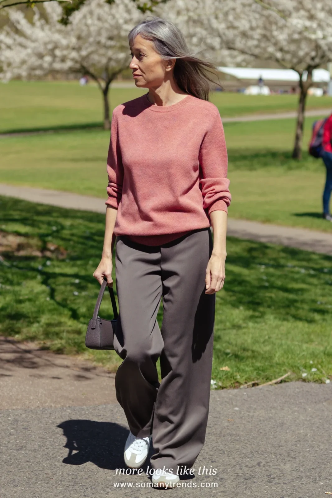 Woman over 50 in a dusty pink fine-knit sweater, wide-leg gray pants and white leather sneakers, outfit 3