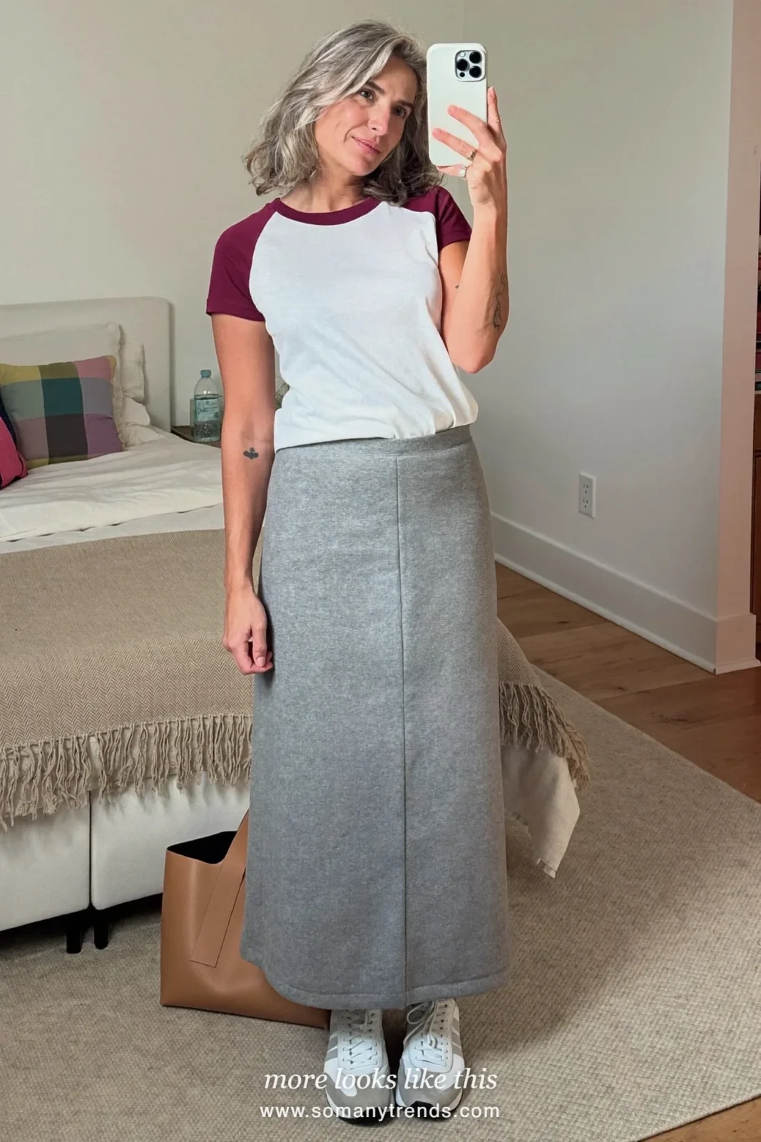 Woman over 50 in a long gray column skirt, white and burgundy baseball tee and white sneakers, outfit 8
