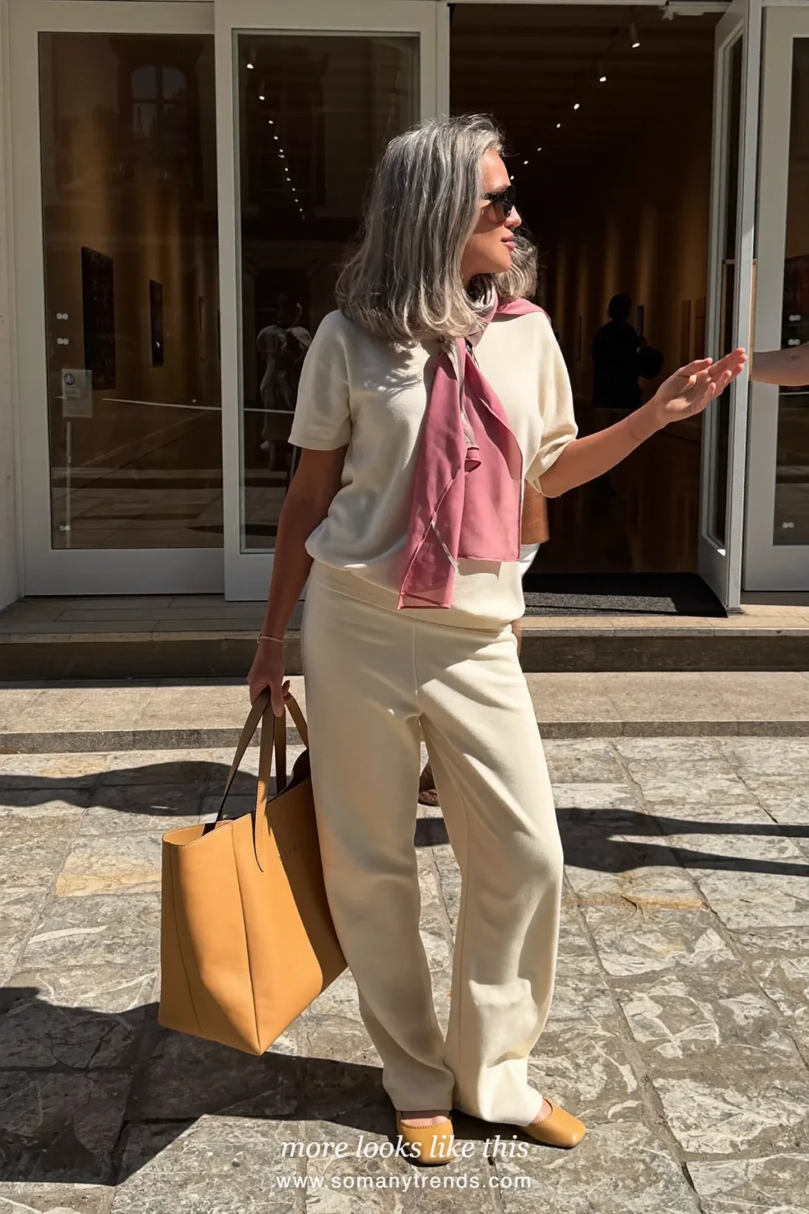 Woman over 50 in a cream relaxed knit two-piece set with a dusty pink silk scarf and tan flats, outfit 13