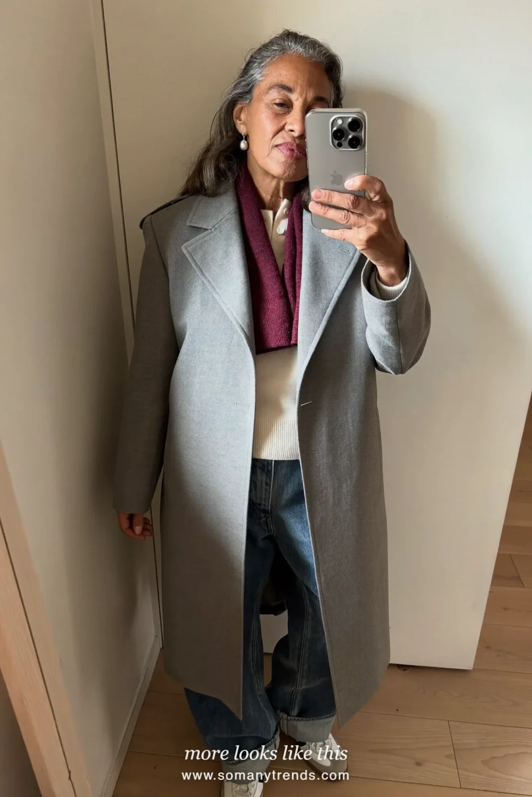 Woman over 50 in a gray trench coat, burgundy scarf, wide-leg jeans and leather sneakers, outfit 24