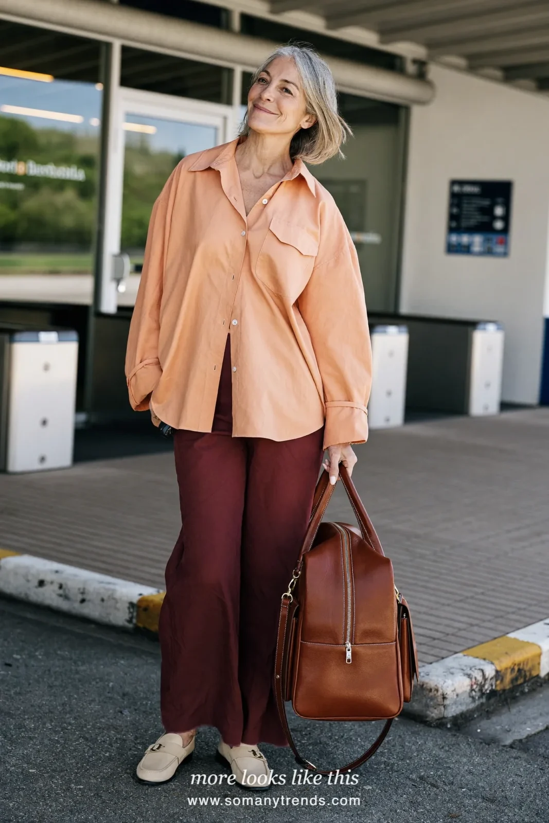 Woman over 50 in a loose peach shirt, wide burgundy pants and cream loafers, outfit 26