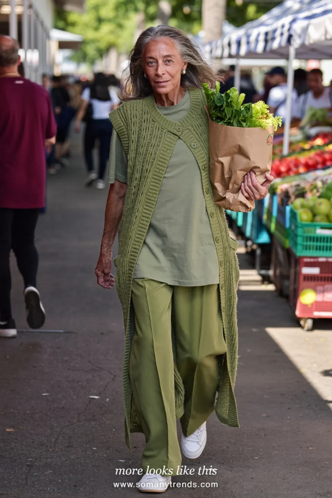 Woman in her seventies in a long sage knit vest over a sage tee, sage wide-leg pants and low sneakers, look 5