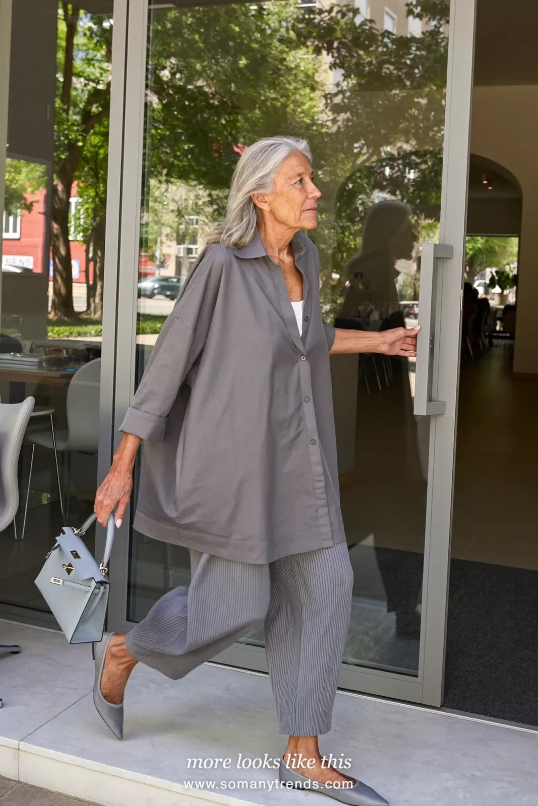 Woman in her seventies in a silver-gray blouse, gray pleated pants and pointed flats, look 9
