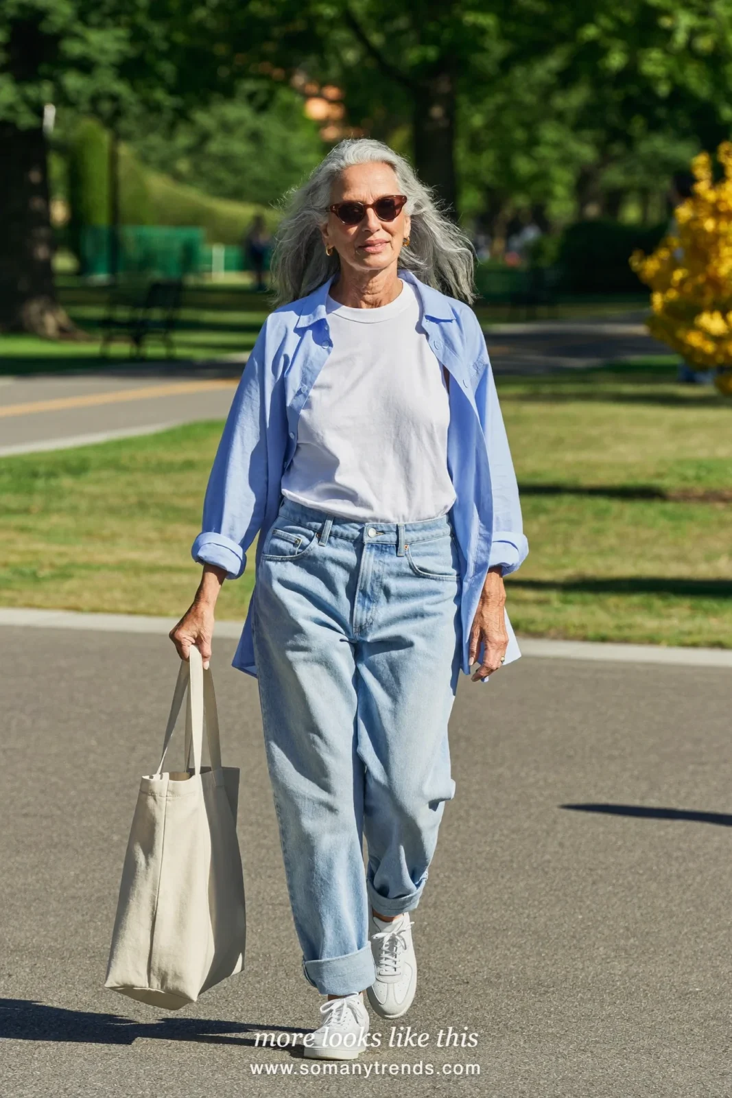 Woman in her seventies in a white tee, icy blue overshirt, light barrel jeans and white sneakers, look 10