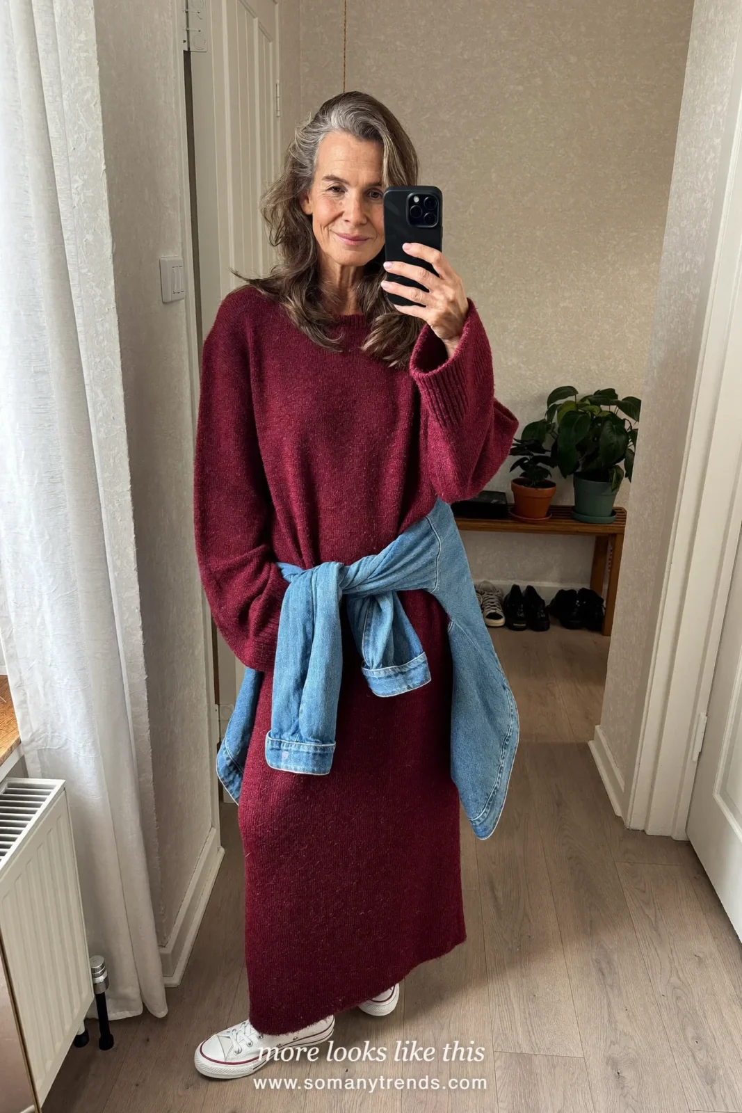 Woman over 50 in a loose burgundy knit maxi dress, white sneakers and a denim jacket tied at the waist, outfit 16