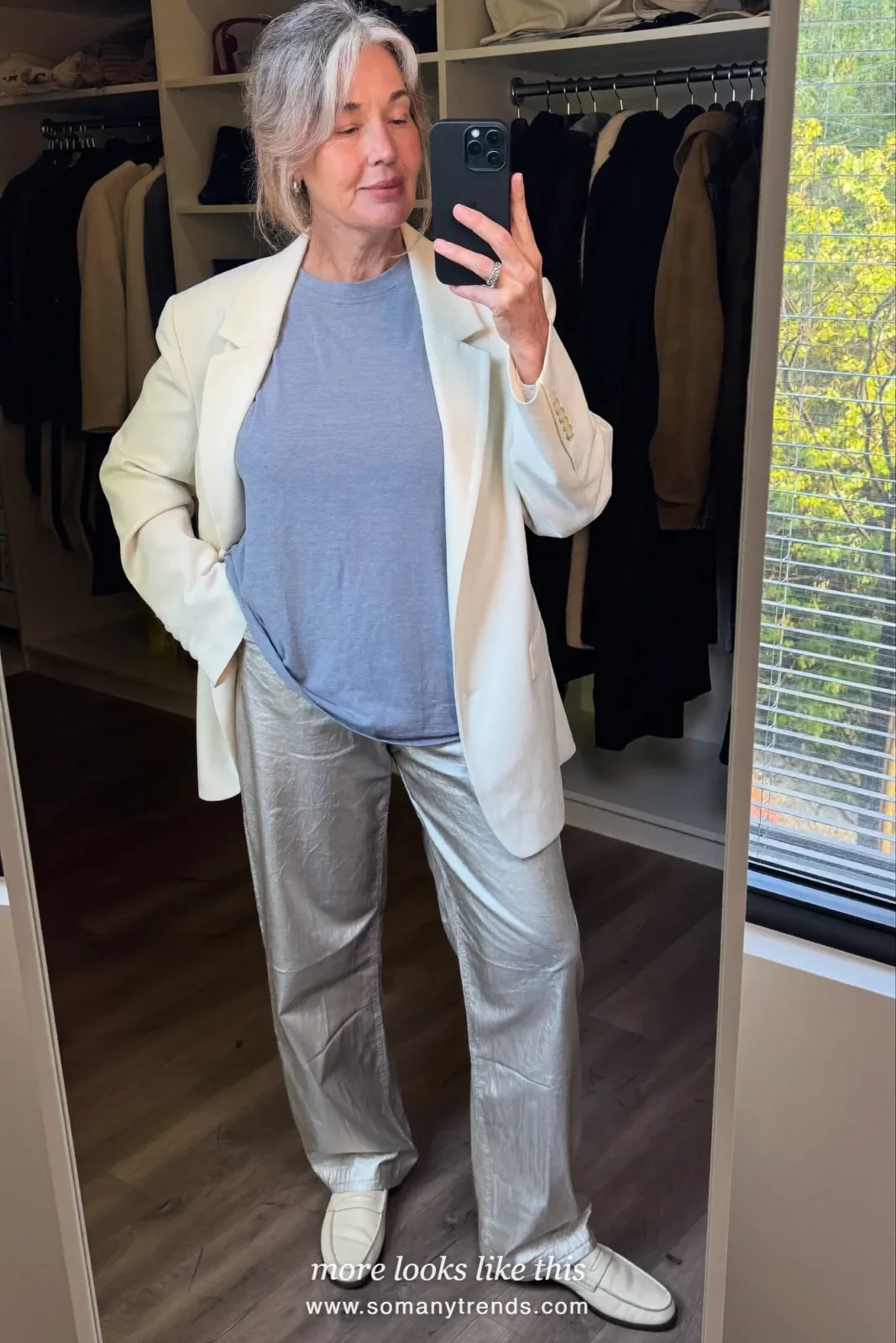 Woman in her seventies in an ivory soft blazer, pale blue tee, wide pants and loafers, look 20