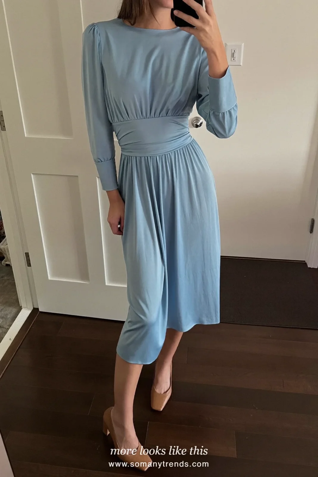 Woman in a powder blue midi dress under a belted camel coat with block heels outside a church, wedding guest outfit 12