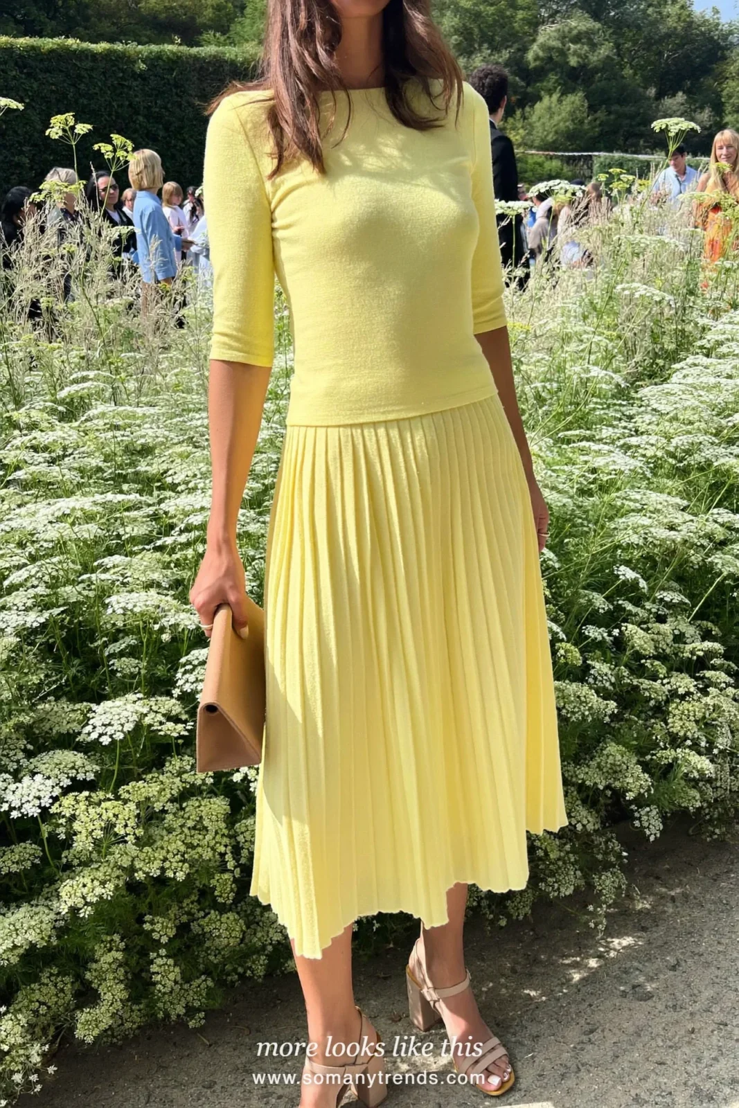 Woman in a butter yellow knit top and pleated midi skirt with tan sandals at a garden wedding, wedding guest outfit 21