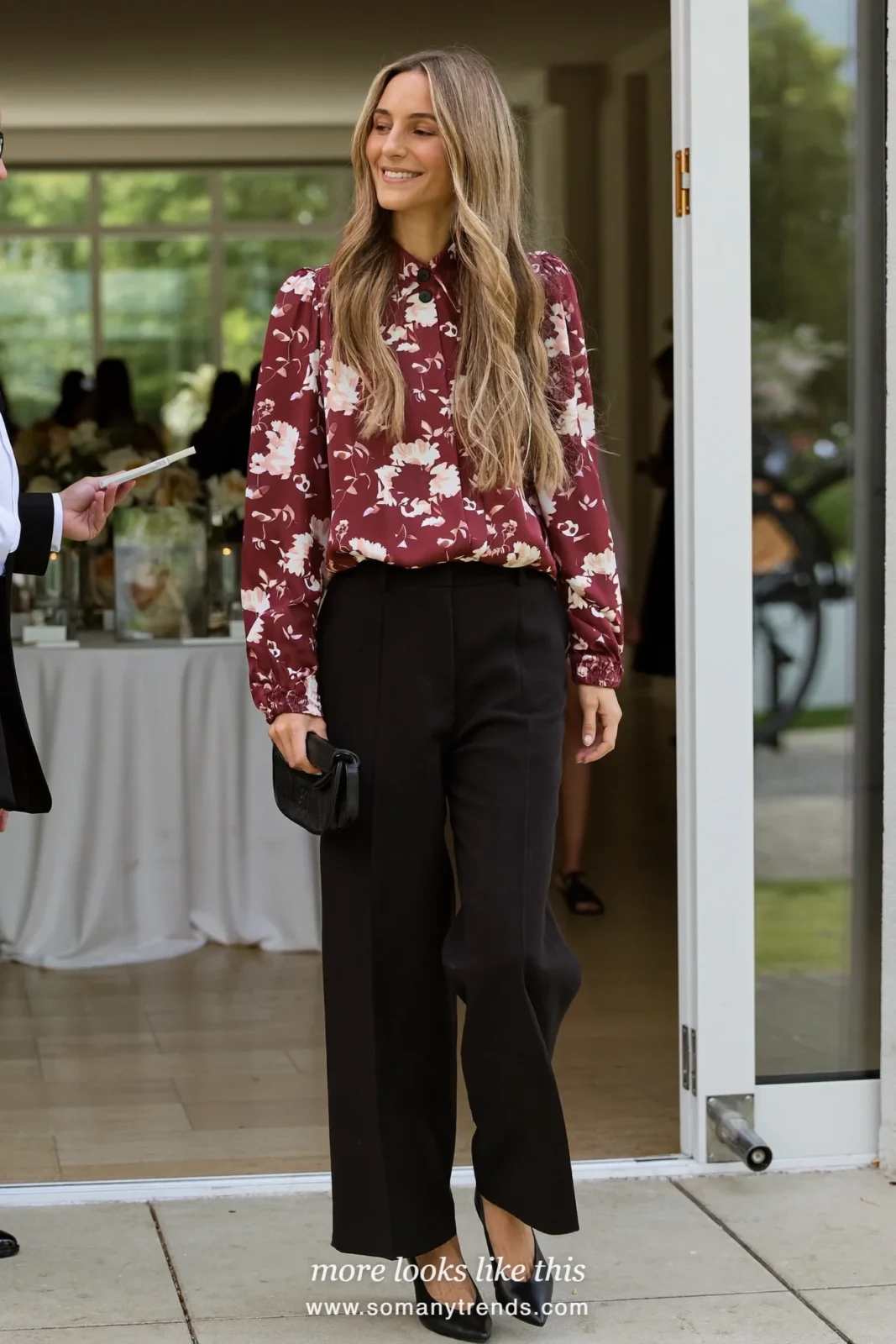Woman in a wine floral blouse and black wide-leg pants with pointed pumps at a venue, wedding guest outfit 23