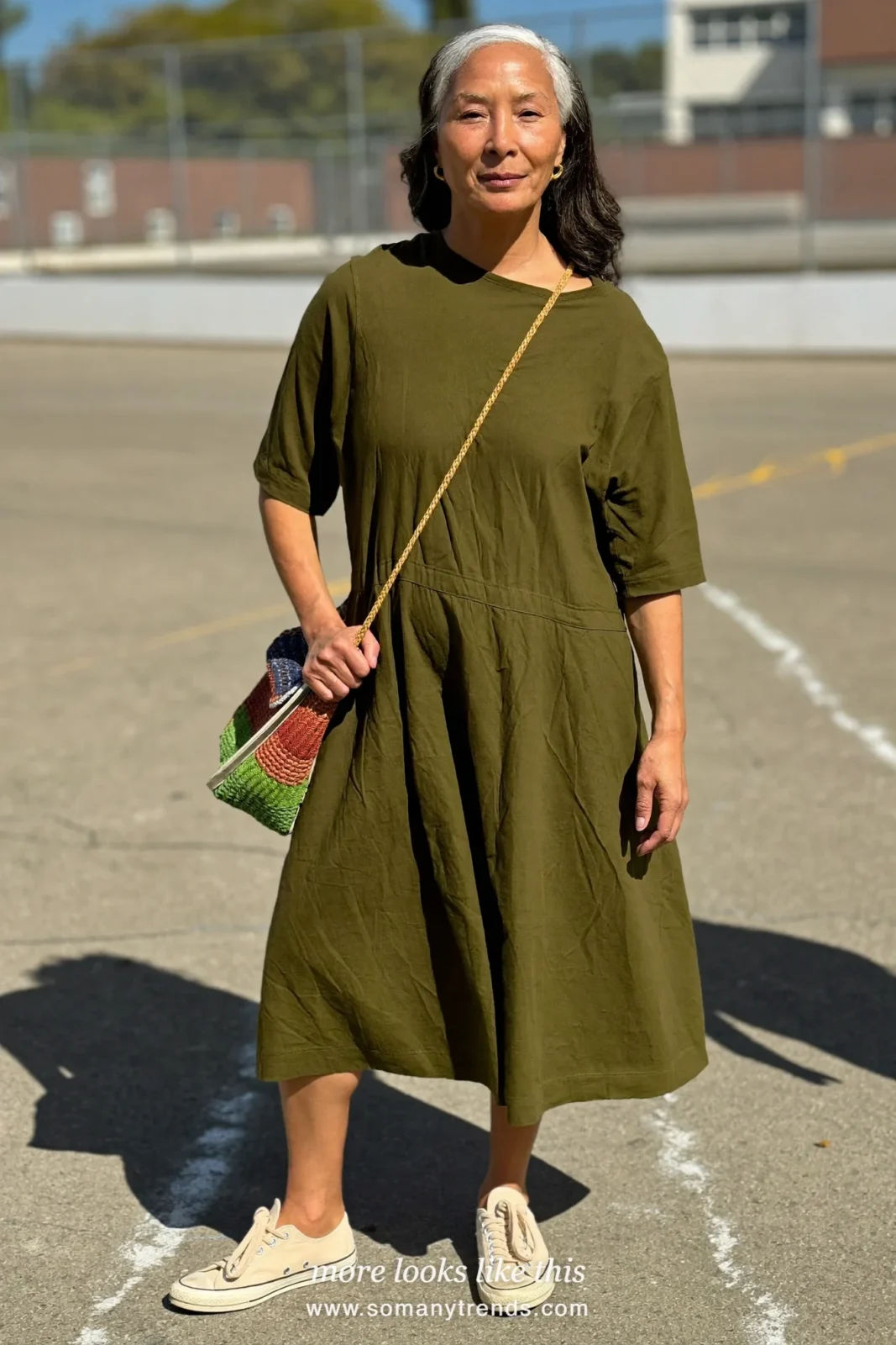 Woman in her forties wearing olive cotton drop-waist knee-length dress with elbow sleeves and cream sneakers, outfit 21