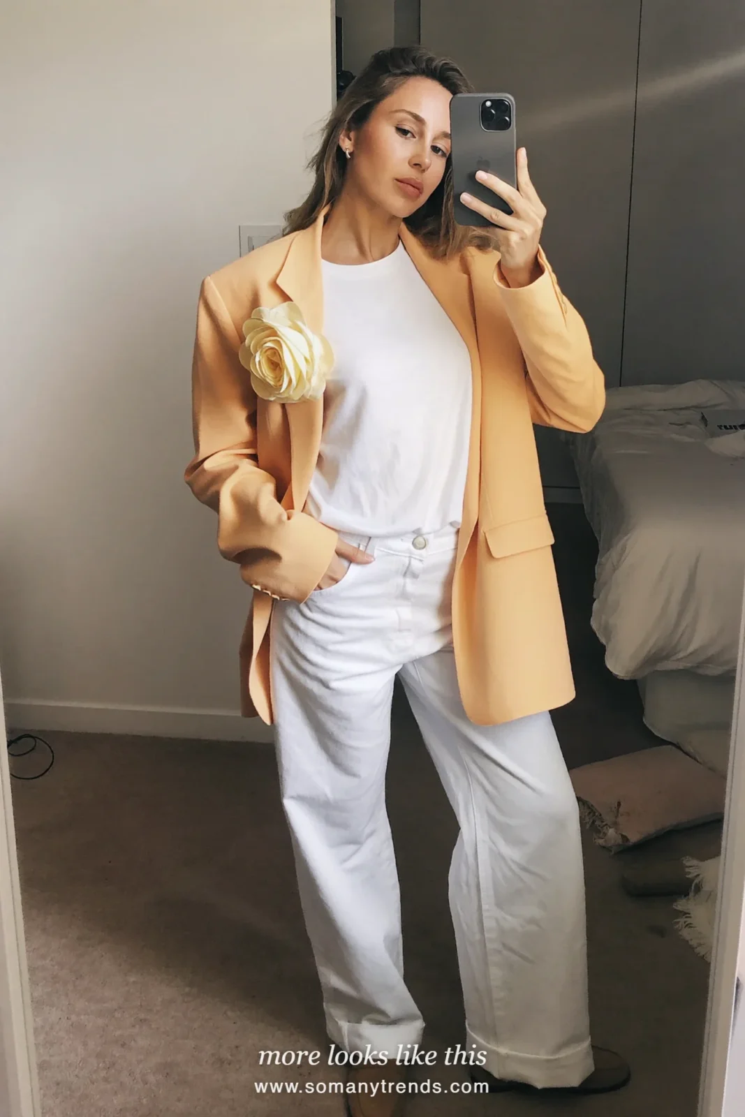 Woman in a peach relaxed blazer with flower lapel pin, white tee, white straight jeans and tan loafers, Easter outfit 8