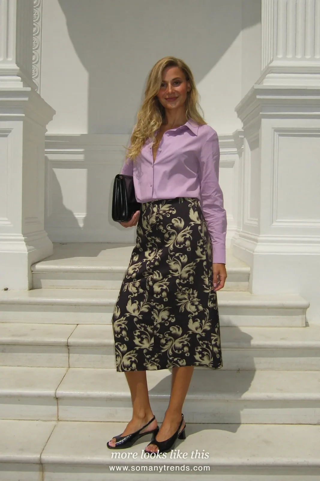 Woman in a lilac blouse, black jacquard midi skirt and black block-heel sandals at a church door, wedding guest outfit 5