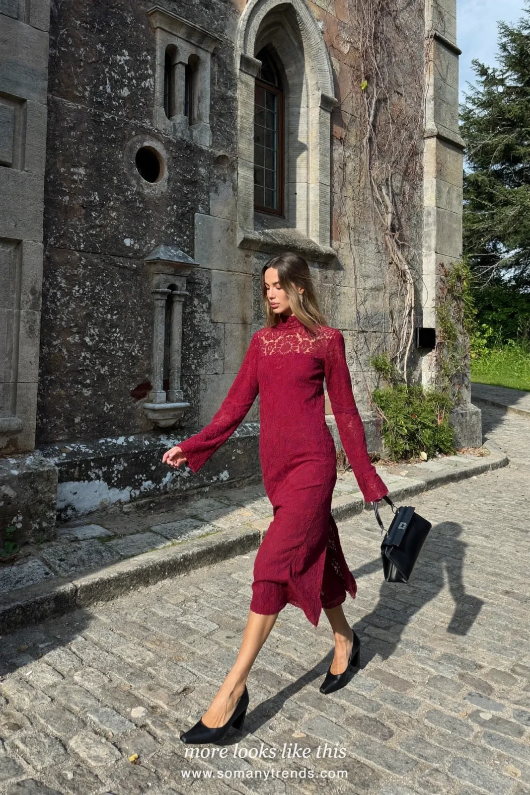 Woman in a wine red lace long-sleeve midi dress with black pumps and bag outside a church, wedding guest outfit 10