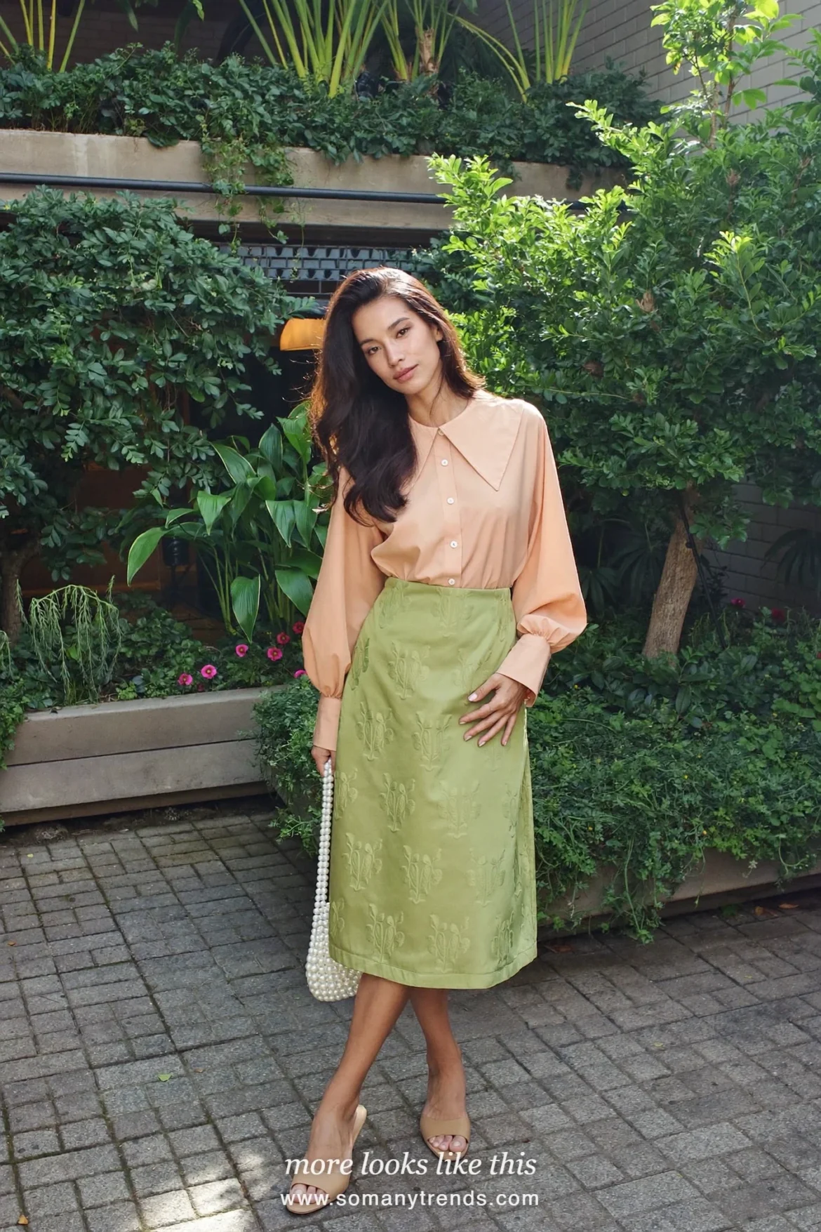 Woman in a sage brocade midi skirt, blush blouse and wedge sandals with a pearl bag at a garden, wedding guest outfit 29